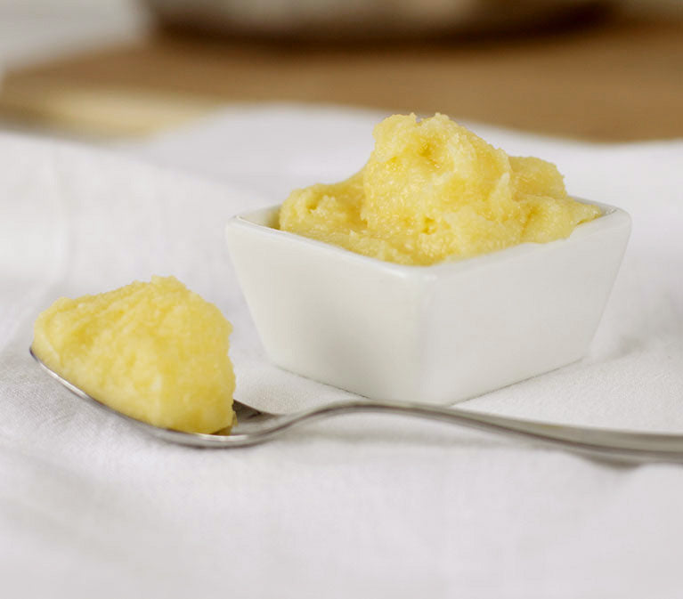a spoonful of ghee next to a bowl full of ghee