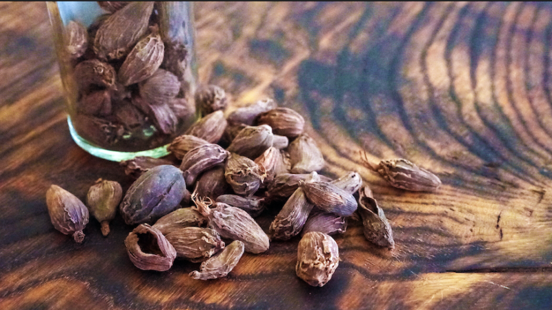 black cardamom pods on a wooden surface