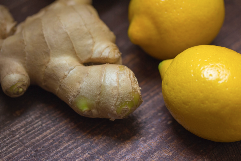 a ginger root on a wooden surface next to some lemons
